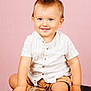 toddler, child, smile, blue_eyes, white_shirt, tan_shorts, sitting, studio, portrait, cute, happy, baby, footwear, cushion, background, hands, short_hair, young, indoor, fashion
