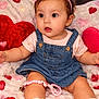 baby, infant, child, denim_overall, headband, bow, sitting, plush_blanket, heart_pattern, red_heart, pillow, sandals, ankle_bracelet, pacifier_clip, big_eyes, curious_expression, portrait, indoor, flowers, couch