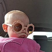 Maya joined the competition — help win amazing prizes! baby, child, sunglasses, pink_clothing, heart_design, car_interior, seat, head, face, ear, window, reflection, person, cute, portrait, fashion, accessory, young_child, casual, indoors