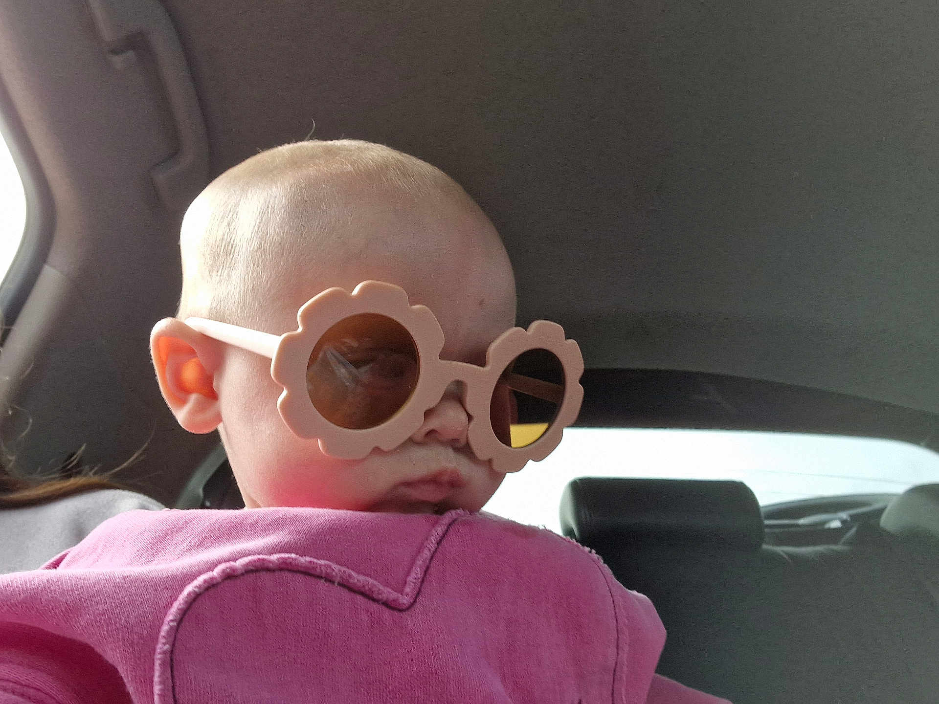 Maya joined the competition — help win amazing prizes! baby, child, sunglasses, pink_clothing, heart_design, car_interior, seat, head, face, ear, window, reflection, person, cute, portrait, fashion, accessory, young_child, casual, indoors