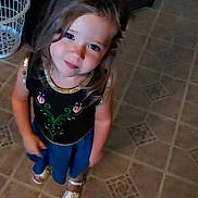 Maggie is registered to the contest to win money with this photo: black_top, blue_skirt, casual_clothing, child, curly_hair, cute, face, floor, girl, happy, home, indoor, laundry_basket, long_hair, looking_up, person, sandals, smiling, standing, tile_floor