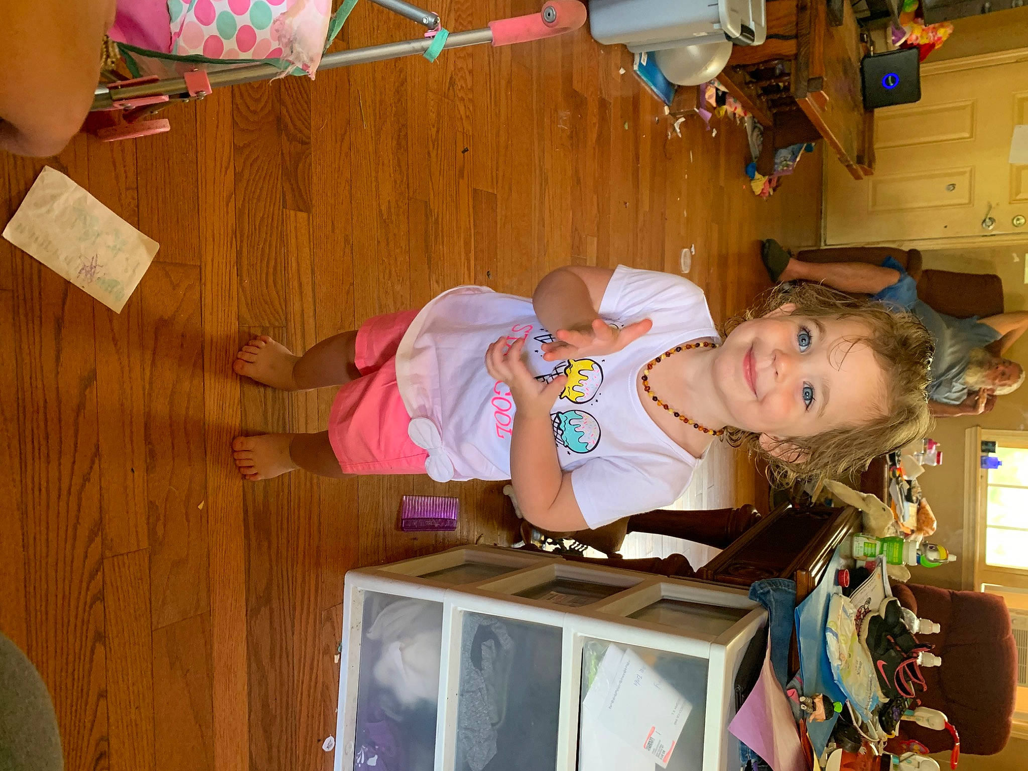 Grace is registered to the contest to win money with this photo: baby, baby_toddler_clothing, child, display_device, fun, hardwood, joy, organ, party, person, pink, play, room, smile, t_shirt, television, television_set, toddler, wood