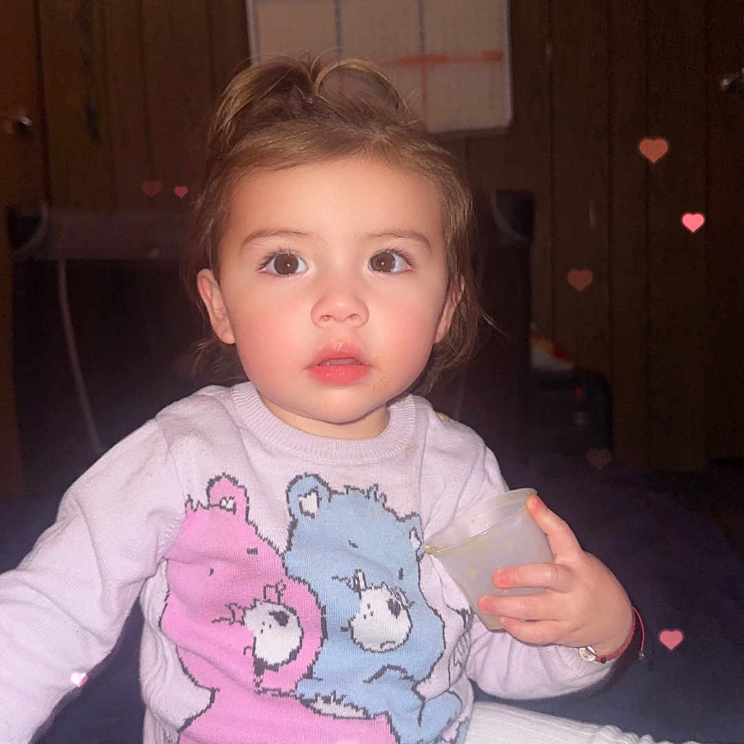 Kaylani is registered to the contest to win money with this photo: applique, baby, bed, bedroom, bodypart, clothing, face, finger, furniture, hand, head, indoors, pants, pattern, person, photography, portrait, room, sitting, t_shirt