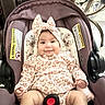 baby, child, infant, car_seat, portrait, smiling, bow, headband, patterned_clothing, dress, harness, sitting, indoors, vehicle, travel, baby_gear, face, eyes, happy, safe