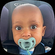 Tahji is registered to the contest to win money with this photo: baby, pacifier, car_seat, child, close_up, face, eyes, infant, seatbelt, purple_cushion, cute, toddler, portrait, child_seat, young_child, head, skin, expression, comfort, seat