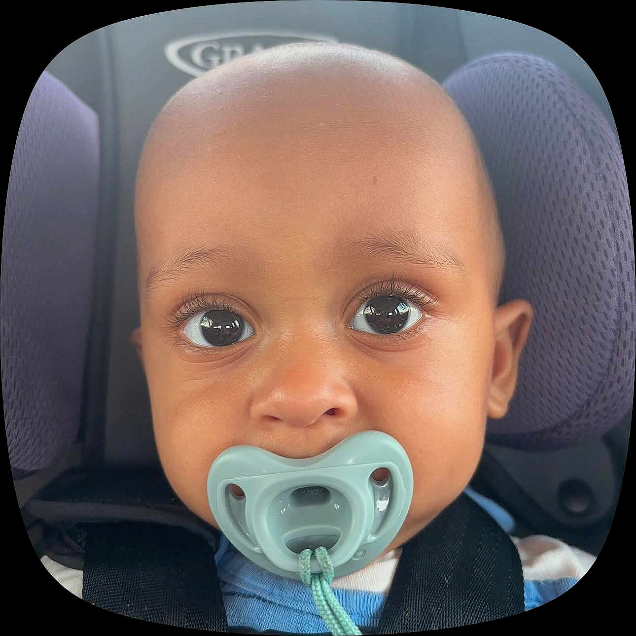Tahji is registered to the contest to win money with this photo: baby, pacifier, car_seat, child, close_up, face, eyes, infant, seatbelt, purple_cushion, cute, toddler, portrait, child_seat, young_child, head, skin, expression, comfort, seat