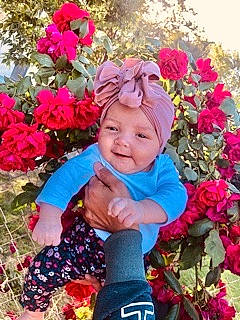 Breanna is registered to the contest to win money with this photo: baby, baby_toddler_clothing, botany, flower, flower_arranging, flowering_plant, grass, happy, headwear, leaf, magenta, nature, people_in_nature, person, petal, photograph, pink, plant, rose_family, smile