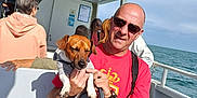Ulysse participe au concours pour gagner de l'argent avec cette photo : animal, boat, casual_clothing, daytime, dog, hoodie, leash, man, outdoor, people, pet, relaxed, sea, seated, sky, sunglasses, sunny, transportation, vacation, water