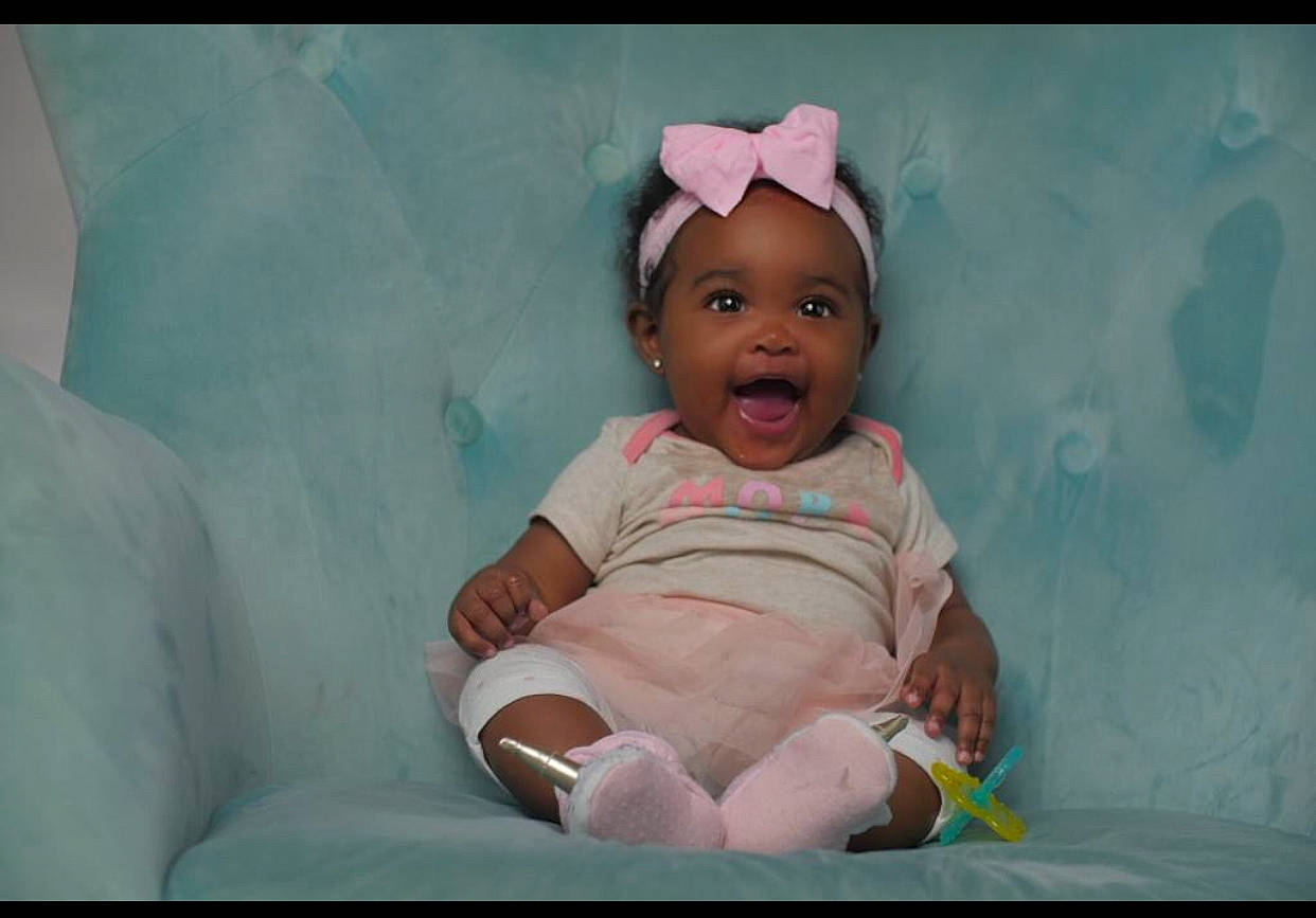 Sadie is registered to the contest to win money with this photo: arm, baby, birth, cheek, child, eye, face, facial_expression, fun, happy, head, headwear, human, mouth, people, person, photography, pink, sitting, skin