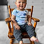 toddler, child, smiling, wooden_chair, animal_print, shirt, pants, barefoot, indoors, portrait, happy, cute, seated, face, hands, feet, hair, furniture, blurred_background, color_pop