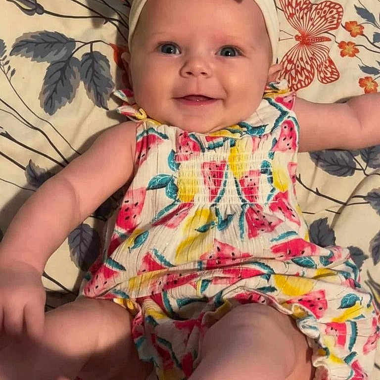 Pearllynn joined the competition — help win amazing prizes! baby, infant, smiling, headband, bow, colorful_clothing, watermelon_pattern, floral_blanket, laying_down, happy, cute, child, playful, legs, arms, skin, face, indoors, portrait, person