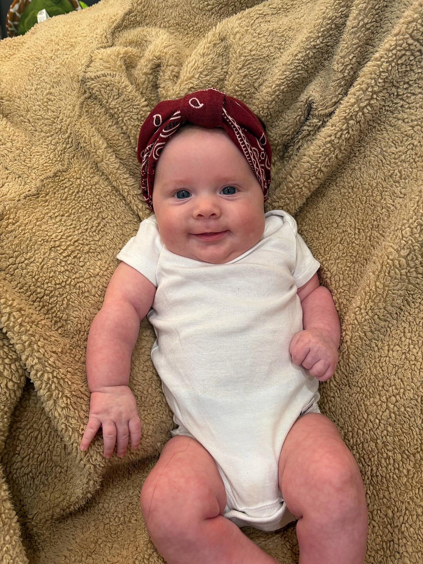 Sofia is registered to the contest to win money with this photo: baby, beige, blanket, child, chubby, cute, face, hand, happy, headband, indoors, infant, legs, lying_down, onesie, portrait, red_bandana, skin, smiling, soft_texture