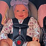 baby, car_seat, child, smiling, headband, floral_clothing, safety_harness, pink, grey, infant, seatbelt, portrait, indoors, cute, happy, sitting, child_seat, car, young_child, closeup