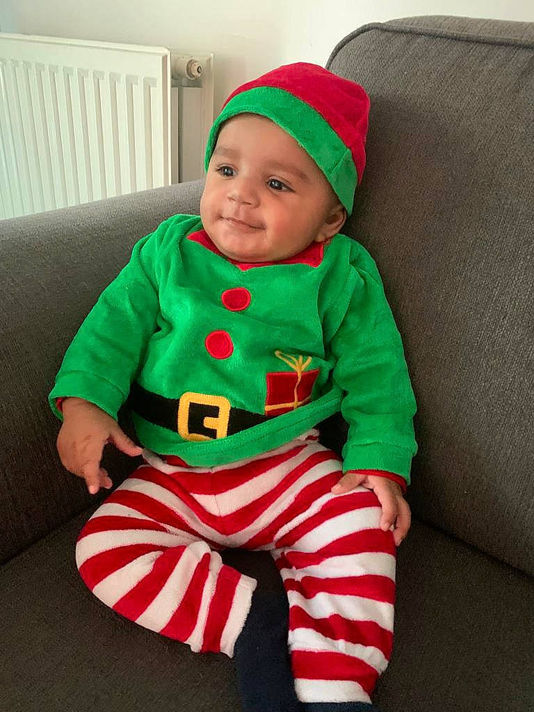 Renzo a rejoint le concours — aidez-le/la à gagner de superbes lots ! baby, baby_toddler_clothing, christmas_decoration, comfort, costume_hat, couch, event, face, fictional_character, happy, hat, head, headwear, lap, outerwear, person, sleeve, smile, sportswear, t_shirt