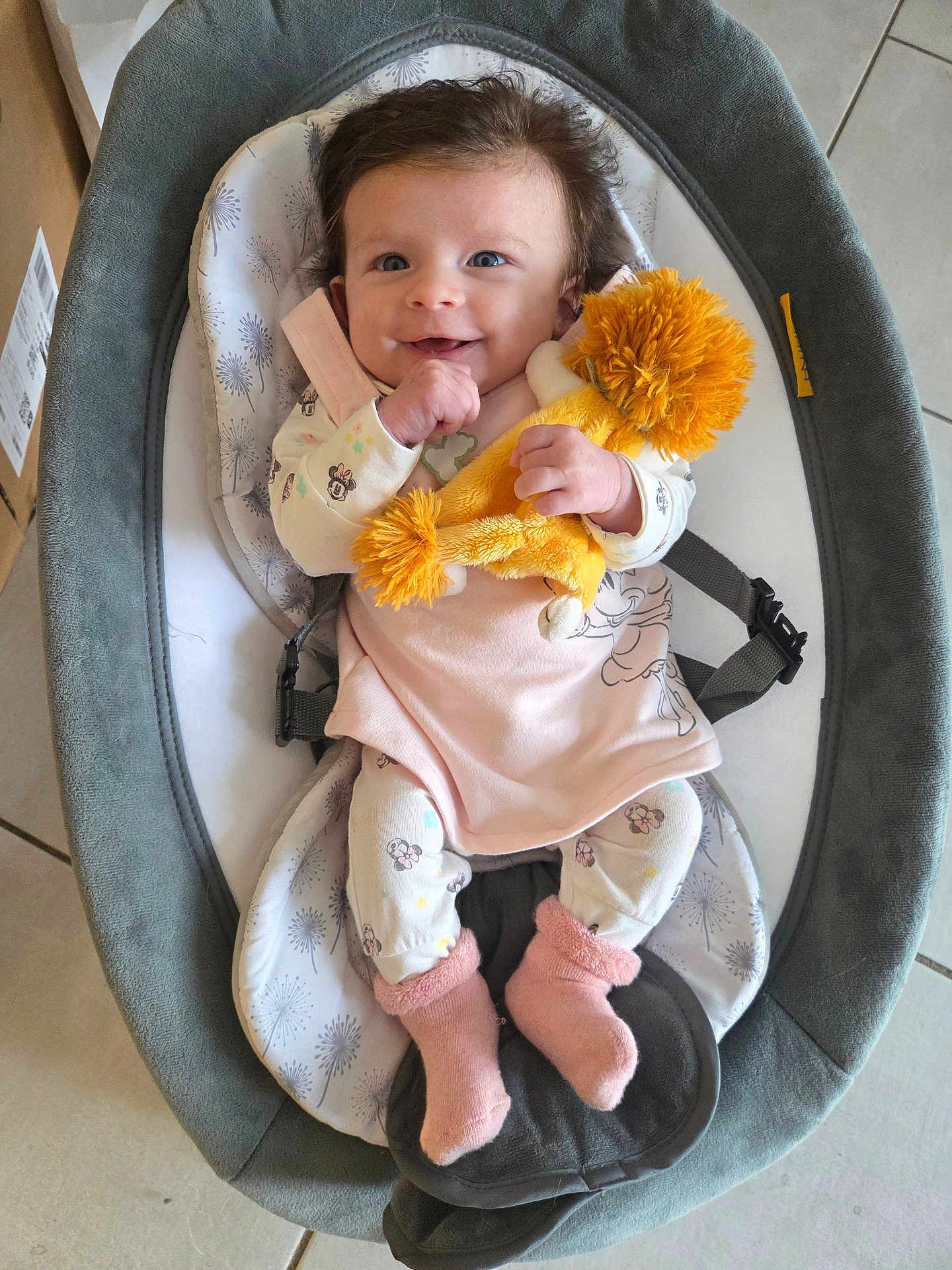 Ambre participe au concours pour gagner de l'argent avec cette photo : baby, infant, smiling, stuffed_toy, lion_plush, baby_rocker, pajamas, pink_socks, floor_tiles, happy, child, cute, indoor, clothing, soft_toy, person, portrait, seated, baby_girl, toy