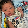Jose is registered to the contest to win money with this photo: baby, infant, mickey_mouse, blanket, plush_toy, clothing, face, person, cute, child, soft_toys, bed, sleepwear, expression, newborn, wrapped, comfort, indoors, portrait, casual
