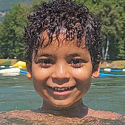 Kaïs participe au concours pour gagner de l'argent avec cette photo : child, boy, smile, water, lake, swimming, curly_hair, outdoor, nature, trees, mountains, summer, sunlight, happy, face, head, person, recreation, holiday, leisure