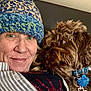 Clarence joined the competition — help win amazing prizes! person, dog, hat, knitted_hat, collar, cross_pendant, closeup, indoor, couch, brown_dog, green_eyes, smile, furry, cozy, portrait, striped_shirt, button, face, pet, snuggle
