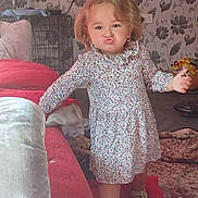 Indiana-Violet joined the competition — help win amazing prizes! carpet, child, couch, curly_hair, cute, earrings, expression, floor, floral_dress, footwear, furniture, home, indoor, living_room, pattern, person, pout, standing, toy, wallpaper