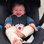 Naoh participe au concours pour gagner de l'argent avec cette photo : baby, child, car_seat, smiling, happy, infant, safety_harness, clothing, blue_sweater, beige_pants, barefoot, cute, outdoor, seat, infant_face, joy, hands, feet, skin, person