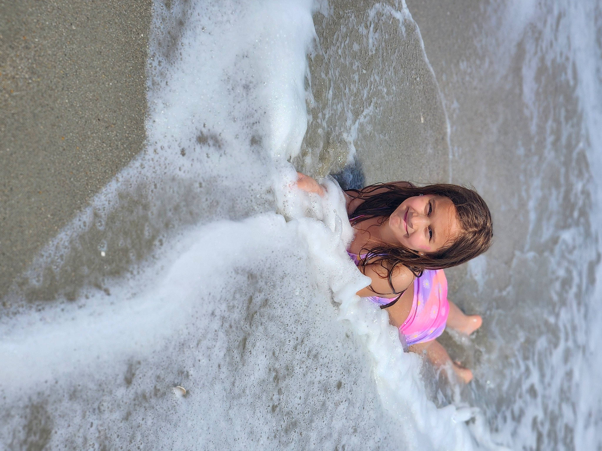 Felicity is registered to the contest to win money with this photo: adventure, bathing, beach, body_of_water, child, freezing, fun, geological_phenomenon, happy, joy, leisure, ocean, person, rapid, recreation, rock, smile, water, water_feature, wave