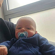 Aylane a rejoint le concours — aidez-le/la à gagner de superbes lots ! adult, arm, baby, caregiver, casual, close_up, clothing, face, hand, hoodie, indoor, infant, natural_light, pacifier, parent, portrait, seated, soft_light, sweater, window