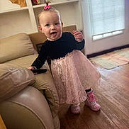 Everleigh joined the competition — help win amazing prizes! baby, toddler, child, portrait, smiling, happy, standing, dress, pink_dress, lace, boots, hair_bow, topknot, living_room, sofa, leather_sofa, wooden_floor, window, indoor, remote_control