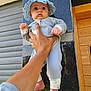 baby, child, hand, hat, blue_hat, infant, clothing, foot, barefoot, person, wall, tiles, wooden_door, outdoor, holding, portrait, cute, expression, skin, fingers