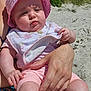 baby, child, pink_hat, bib, beach, sand, sunlight, adult_hand, outdoor, summer, nature, grass, blue_sky, portrait, cute, infant, skin, clothing, person, holding