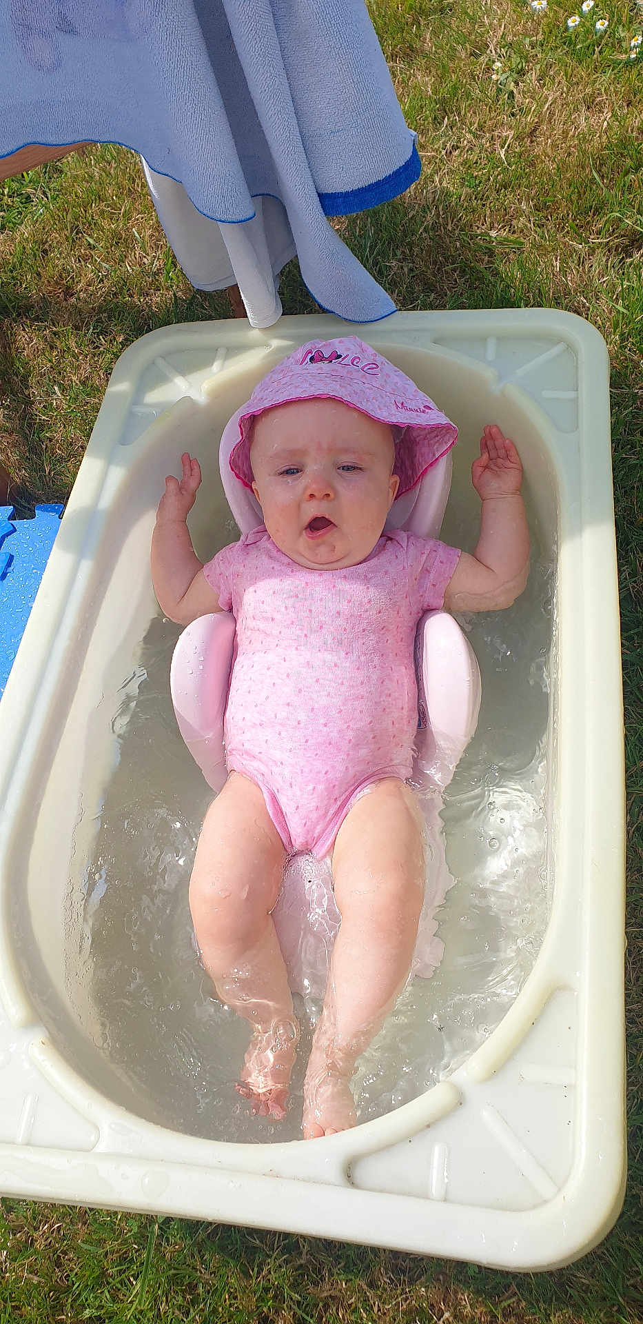 Ashley a rejoint le concours — aidez-le/la à gagner de superbes lots ! baby, bathtub, water, pink_onesie, pink_hat, outdoor, grass, towel, summer, child, infant, sunny, relaxing, splashing, plastic_tub, cute, skin, legs, arms, headwear