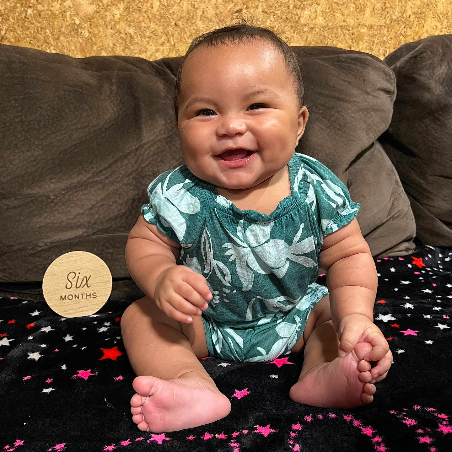 Amrielle joined the competition — help win amazing prizes! baby, blanket, brown, child, couch, cute, face, floral_pattern, foot, green_clothing, hand, happy, indoors, infant, portrait, sitting, smiling, stars, text, wooden_sign