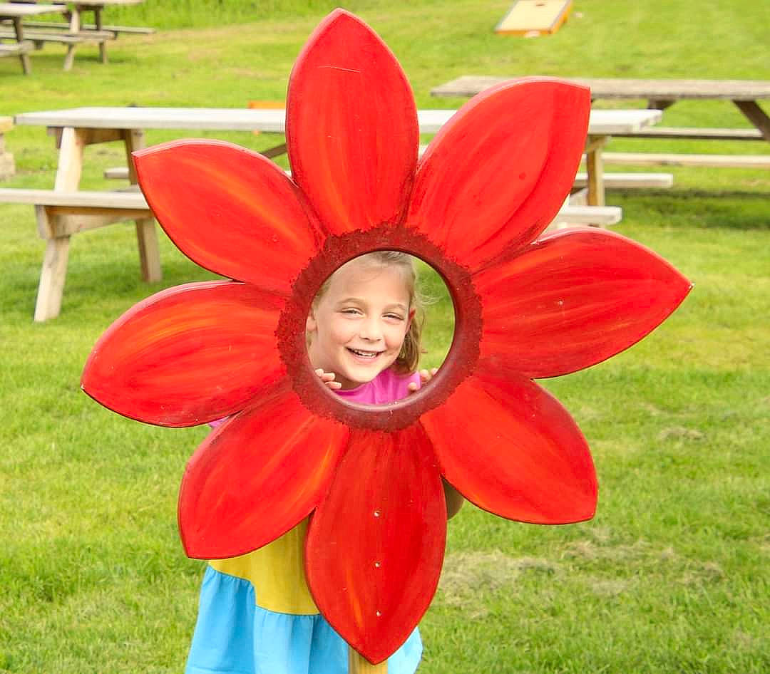 Abigail is registered to the contest to win money with this photo: auto_part, automotive_wheel_system, child, flower, flowering_plant, fun, grass, happy, joy, leisure, magenta, outdoor_bench, outdoor_furniture, person, petal, plant, propeller, recreation, table, toddler