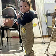 Lyam a rejoint le concours — aidez-le/la à gagner de superbes lots ! child, toddler, indoor, floor, clothing, overalls, lion_king, tile, person, smile, face, cute, standing, blurry_background, furniture, home, cloth, shoes, baby, holding