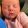 baby, newborn, sleeping, infant, pink_shirt, text_on_clothing, closeup, face, peaceful, soft_light, human, child, portrait, cuddling, skin, head, cute, happy, clothing, resting