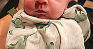 Chance joined the competition — help win amazing prizes! baby, infant, blanket, dinosaur_pattern, face, eyes, hand, watch, clothing, furniture, footwear, person, indoor, portrait, expression, skin, head, sitting, holding, casual