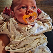 Chance joined the competition — help win amazing prizes! baby, pacifier, onesie, infant, hand, wooden_background, clothing, face, newborn, cute, portrait, closeup, child, sleepwear, human, soft_lighting, indoors, expression, holding, resting