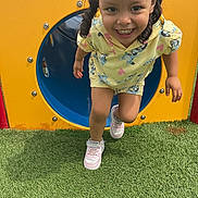 Mia joined the competition — help win amazing prizes! child, girl, smiling, playground, tunnel, yellow_clothing, pink_shoes, grass, outdoor, happy, curly_hair, pigtails, running, fun, play, daylight, colorful, casual_wear, active, person