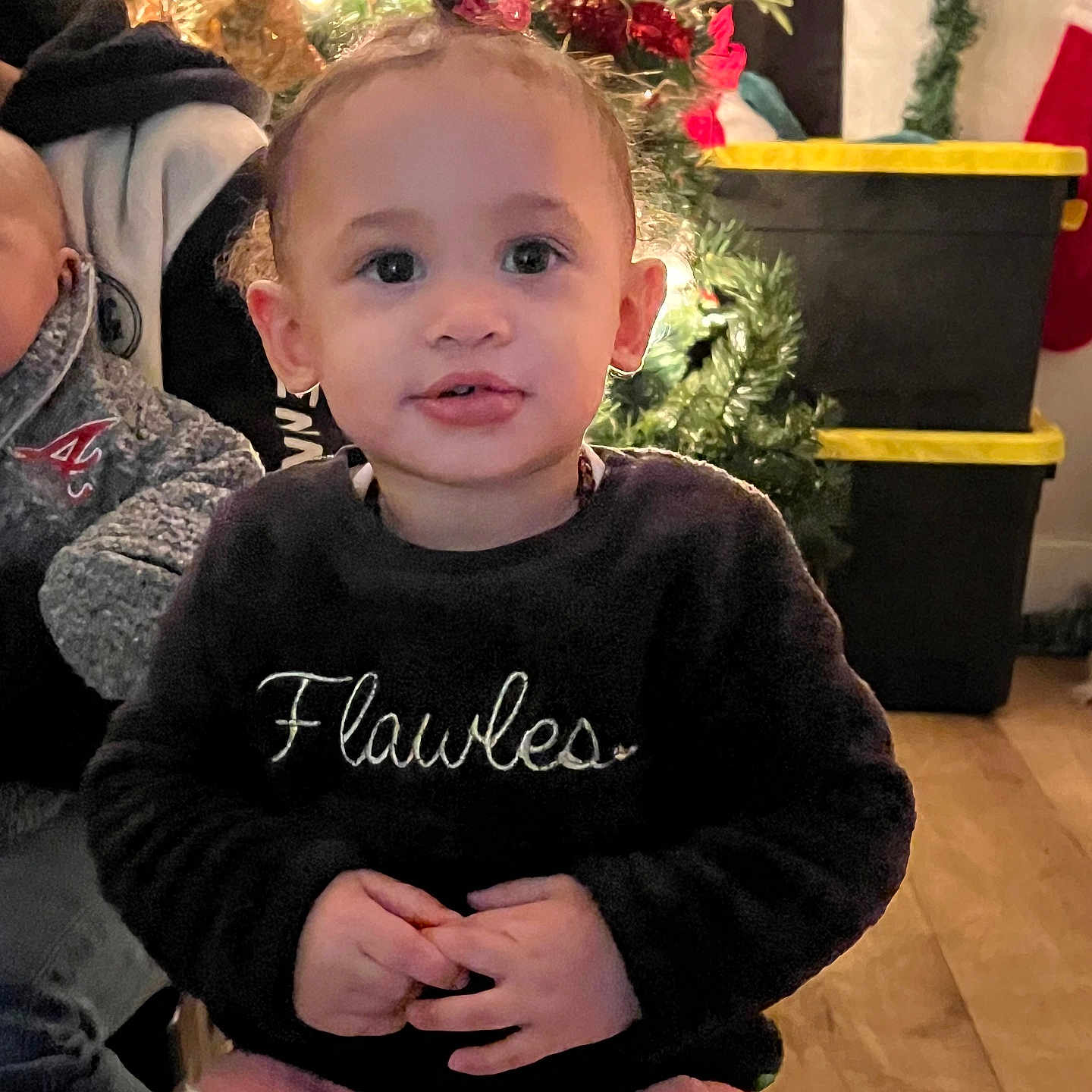 Kaliyah is registered to the contest to win money with this photo: baby, bodypart, clothing, coat, face, finger, hand, head, indoors, jacket, knitwear, pants, person, photography, plant, portrait, pottedplant, sitting, sweater, tree