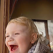 Aries joined the competition — help win amazing prizes! child, toddler, smiling, laughing, blonde_hair, window, wood, fleece_jacket, cozy, indoor, sunlight, blinds, happy, face, portrait, cute, warm_clothing, expression, person, head