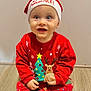 toddler, child, baby, christmas, holiday, festive, santa_hat, red_clothing, sitting, floor, wooden_floor, pajamas, smiling, cute, indoors, portrait, young_child, winter_clothing, holiday_season, festive_sweater