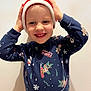 Lisa a rejoint le concours — aidez-le/la à gagner de superbes lots ! child, smiling, holiday_hat, christmas_sweater, festive, happy, portrait, indoor, young_child, cute, holiday_theme, red_hat, blue_sweater, person, clothing, face, hands, joyful, winter, celebration