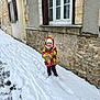Lisa a rejoint le concours — aidez-le/la à gagner de superbes lots ! boots, building, child, cold_weather, curious, daytime, gloves, hat, jacket, outdoor, person, sidewalk, snow, snowy_path, standing, stone_wall, urban, window, winter, winter_clothing