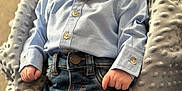 Reggie is registered to the contest to win money with this photo: baby, infant, child, blue_shirt, denim_jeans, blanket, comfortable, soft_texture, casual_clothing, portrait, indoor, cute, small_hands, gazing, serene, resting, cozy, newborn, fashion, relaxed