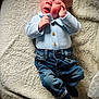 Reggie is registered to the contest to win money with this photo: baby, infant, child, denim_jeans, blue_shirt, socks, blanket, soft_texture, indoor, portrait, cute, lying_down, small_hand, face, expression, light, casual_clothing, cozy, newborn, resting