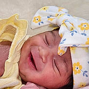 Amelia joined the competition — help win amazing prizes! baby, newborn, smiling, closeup, headband, flower_pattern, yellow_clothing, blanket, infant, cute, peaceful, sleeping, skin, hand, portrait, soft_texture, happy, child, resting, indoors