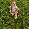 child, toddler, grass, outdoor, greenery, bubble_wands, playful, summer, nature, barefoot, casual_clothing, happy, cute, sitting, toy, daylight, lawn, innocent, young, fun