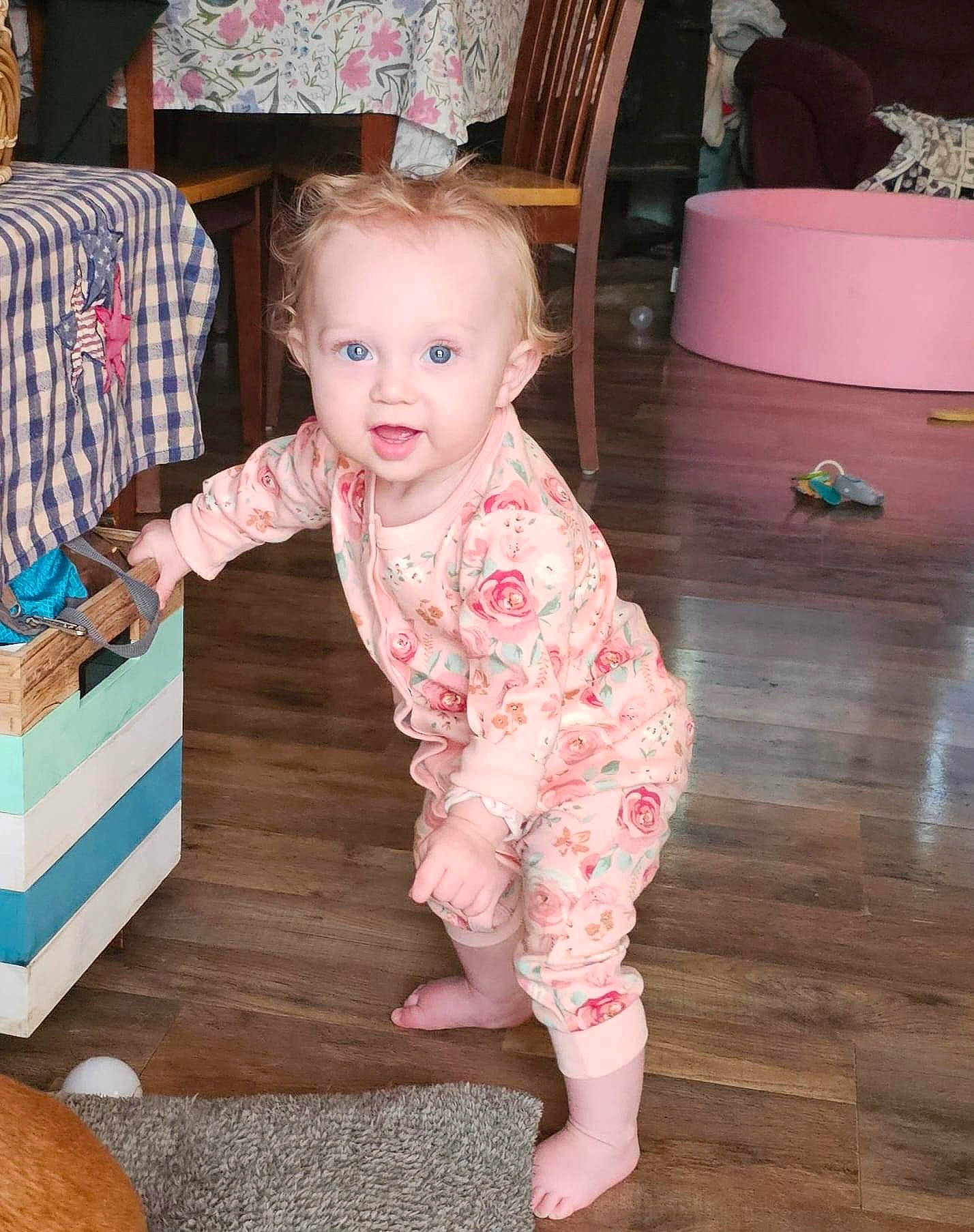 Oaklyn is registered to the contest to win money with this photo: baby, baby_toddler_clothing, cheek, child, event, eye, facial_expression, floor, flooring, foot, fun, hardwood, head, person, pink, skin, sleeve, smile, standing, toddler