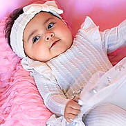 Alora joined the competition — help win amazing prizes! baby, infant, child, pink, white_clothing, headband, blanket, soft, cute, portrait, indoors, hand, face, lying_down, fabric, sparkle, ruffled, gaze, young_child, cozy