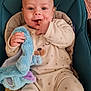 baby, infant, plush_toy, onesie, smile, teal_baby_seat, fingers_in_mouth, happy, child, indoor, soft_toy, cute, cozy, pajamas, sitting, face, skin, hand, comfort, portrait
