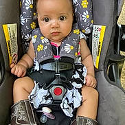 Gernyiah is registered to the contest to win money with this photo: attention, baby, car_interior, car_seat, child, cowboy_boots, cute, dress, expression, floral_pattern, indoors, infant, portrait, safety_harness, seat_padding, seatbelt, small_hands, strapped_in, wide_eyes, young_child